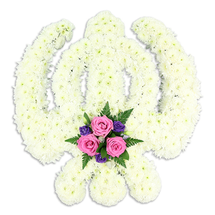 A large, meticulously crafted Khanda floral tribute, symbol of Sikh faith and courage, stands in quiet prominence against a clean white background. Its entire form is clothed in white chrysanthemums, each bloom placed with precision so that the petals touch and overlap, creating a dense, velvety surface. The central double-edged sword rises straight and true, framed by the smooth circular band of the chakkar, while the two curved kirpans sweep downwards and cross neatly at the base. The uniform white, with its subtle creamy undertone, lends the tribute a calm, contemplative aura, softened further by the gentle play of light and shadow across the textured petals. Beneath the central sword, exactly where the blades of the kirpans meet, sits a compact posy of accent flowers that introduces a heartfelt note of colour. Three pink roses, fully opened but still crisp at the edges, form the focal point, their soft spirals suggesting tenderness and affection. Around them, deep purple blossoms-small and delicate-contrast with the pink and echo the dignity of the occasion, while fine green ferns and lush foliage add structure and depth. The composition is balanced and harmonious, combining the purity of white with touches of comforting colour. It is easy to imagine this tribute placed at a Sikh funeral or memorial service in Stevenage, perhaps arriving from a nearby florist who understands local customs and family wishes. The design speaks of reverence, remembrance, and the desire to honour a life with something both spiritually meaningful and naturally beautiful.