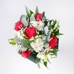 A lush, hand-tied bouquet of red and pink roses, ruffled crimson carnations, and soft white daisies is captured from above, radiating the kind of gentle excitement that comes with a special morning in Stevenage. The roses are bold and velvety, their deep petals opening in confident spirals, while the carnations curl and twist in feathery folds of scarlet and pink-red, adding movement and passion to the heart of the design. Nestled between them, tiny snow-white chrysanthemum daisies and delicate gypsophila form a cloudlike halo, scattering little pools of brightness throughout the arrangement, as if touched by the first light over Fairlands Valley Park. Eucalyptus stems weave outwards in soft arcs, their muted blue-green leaves bringing a cool, modern edge and a faint, refreshing scent that balances the sweetness of the blooms. Behind them, deeper tropical greens anchor everything, their glossy surfaces giving depth and contrast to the lighter petals. The bouquet feels carefully composed yet never stiff; each flower has space to breathe, creating a sense of relaxed elegance, like a thoughtfully dressed table in a quiet Old Town café. It is easy to imagine this arrangement placed by a sunny window in a Stevenage home, celebrating a birthday, a long-awaited reunion, or simply the pleasure of fresh flowers brightening a favourite corner. The colours and textures speak of optimism and heartfelt affection, making the bouquet a comforting, uplifting presence that transforms an ordinary day into something quietly memorable.